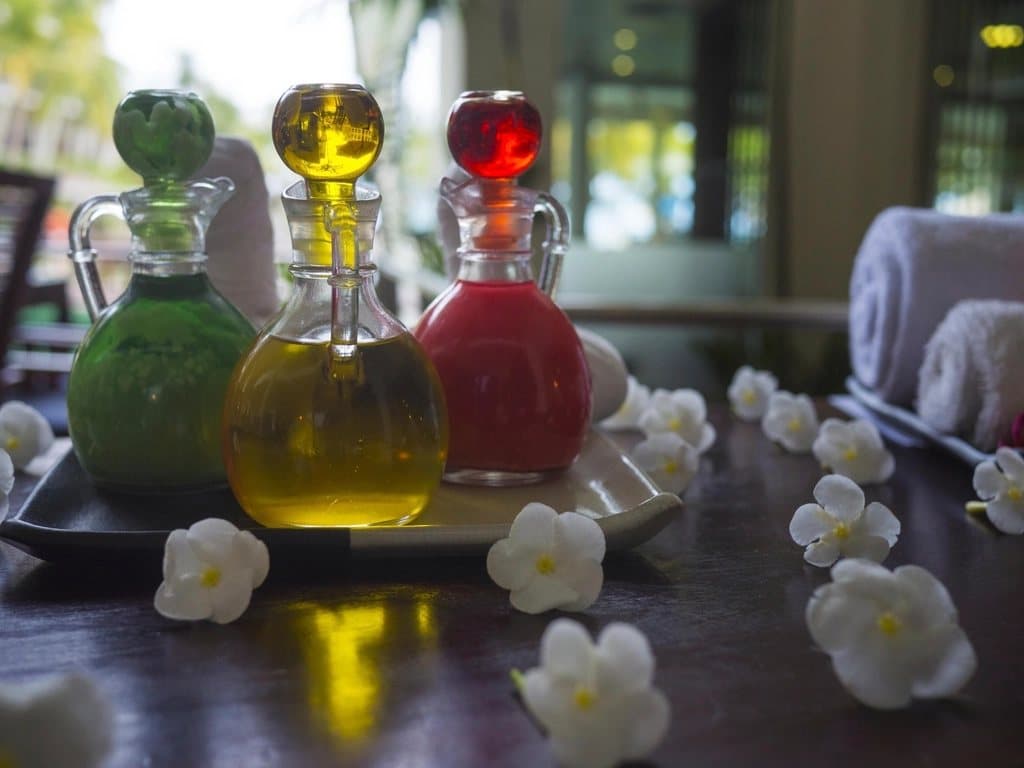 Massage oil bottle with flowers and decorative stones next to it