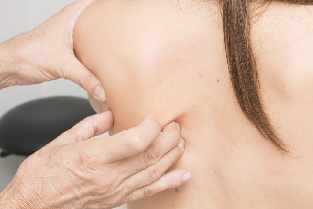 Mãos de massagista aplicando óleo nas costas de uma pessoa